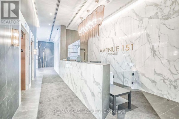 Open concept living and dining area with a desk, sofa, and glass dining table. - 205 - 151 Avenue Road, Toronto