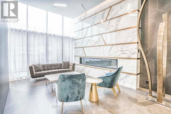 Lounge area with grey sofas, marble fireplace, and large television. - 205 - 151 Avenue Road, Toronto