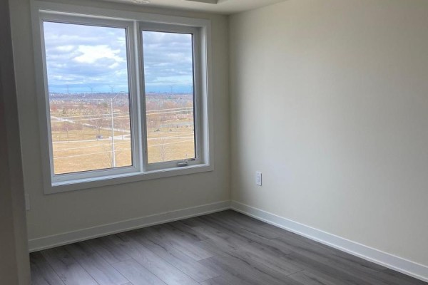 Bedroom with two large windows offering a view of fields and distant buildings. - 205 - 1695 Dersan Street, Pickering