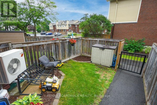Small backyard of the townhouse with a grass lawn, outdoor storage, and AC unit. - 205 - 1760 Cabaret Lane, Ottawa