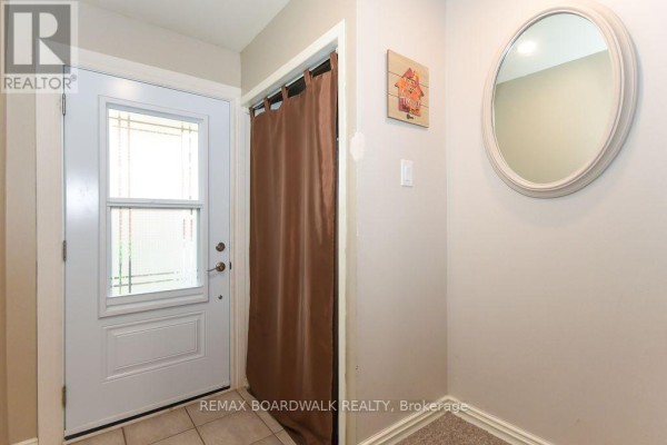 Interior entrance foyer with a white door, beige walls, and a round mirror. - 205 - 1760 Cabaret Lane, Ottawa