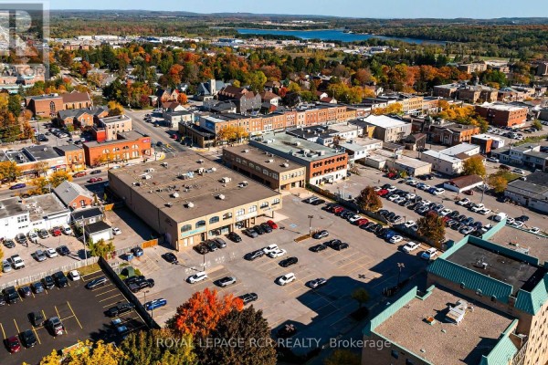 Aerial view of commercial buildings and downtown Orangeville with trees and lake. - 205 - 190 Broadway, Orangeville