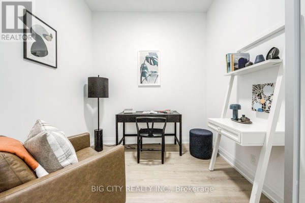 Home office area with a desk, chair, and shelving unit against a white wall. - 205 - 36 Brentcliffe Road, Toronto
