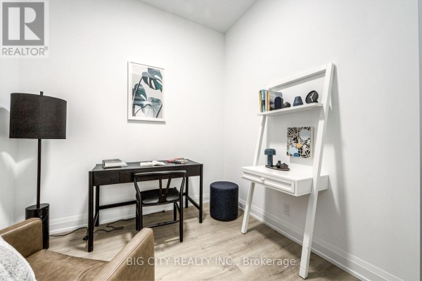 Home office area with a desk, chair, and shelving unit against a white wall. - 205 - 36 Brentcliffe Road, Toronto