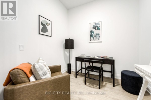 Home office area with a desk, chair, and shelving unit against a white wall. - 205 - 36 Brentcliffe Road, Toronto
