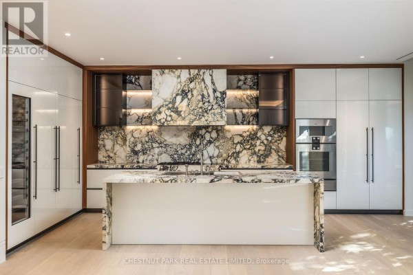 Contemporary kitchen with a large marble island, white high-gloss cabinets, and built-in appliances. - 205 - 7 Dale Avenue, Toronto