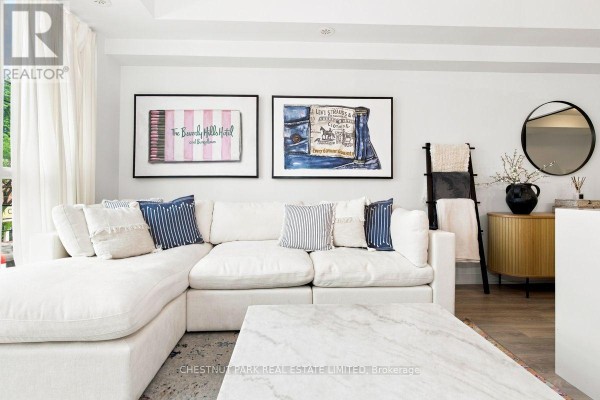 Living room featuring a white sectional sofa, marble coffee table, and artwork. - 205 - 899 Queen Street E, Toronto