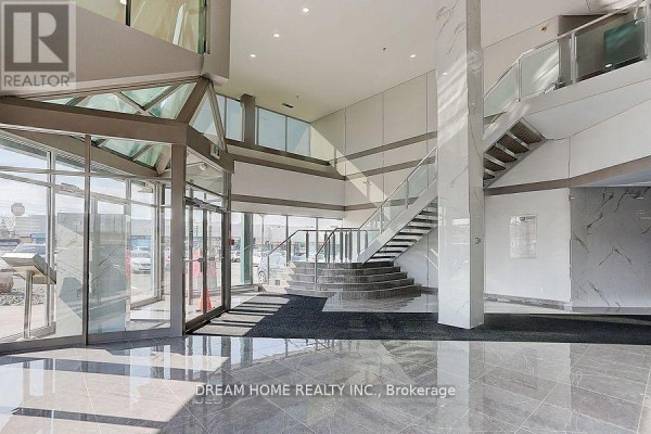 View of the building lobby with a staircase, marble accents, and large windows letting in light. - 205 - A - 7800 Woodbine Avenue, Markham