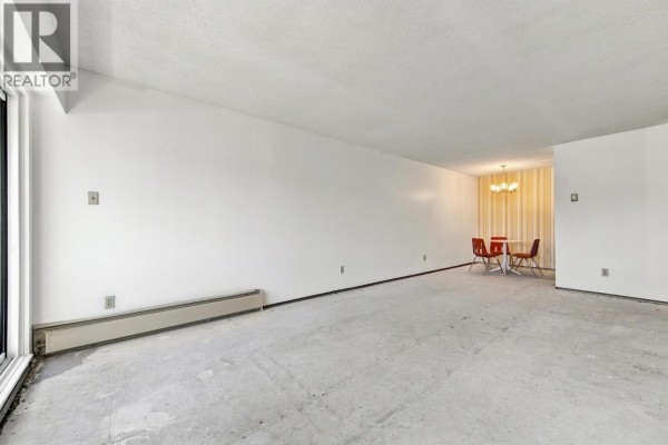 Living and dining area with white walls and bare concrete floors. - 205 1825 W 8th Avenue, Vancouver