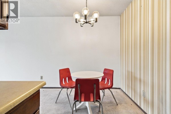 Dining area with four red chairs around a white table. - 205 1825 W 8th Avenue, Vancouver