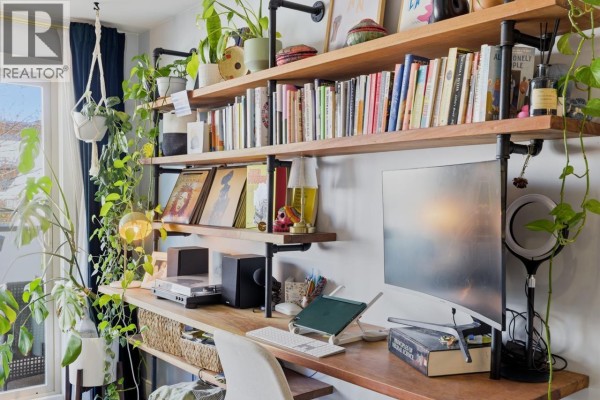 Built-in desk with computer and shelves filled with books, records, and plants. - 205 1864 Frances Street, Vancouver