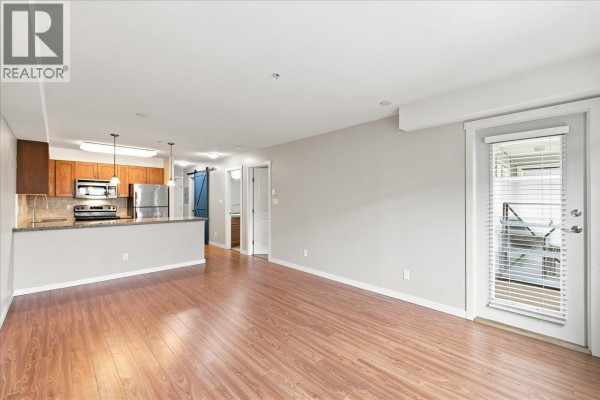 Living room with hardwood floors, a neutral palette, and access to an outdoor balcony area. - 205 2373 Atkins Avenue, Port Coquitlam