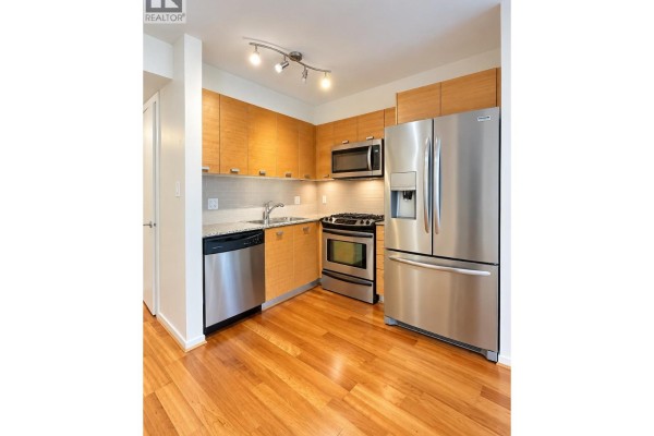 Apartment kitchen featuring light wood cabinets, granite countertops, stainless steel appliances, and a dishwasher. - 205 2482 Spruce Street, Vancouver