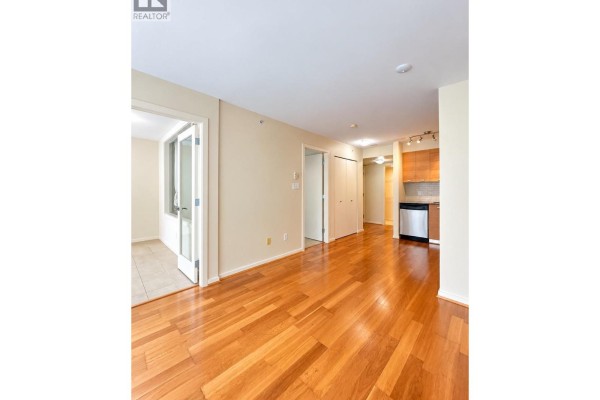 View of the apartment's interior, showcasing hardwood floors, doorways to rooms, and a glimpse of the kitchen. - 205 2483 Spruce Street, Vancouver
