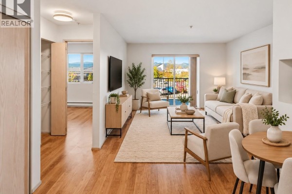 Living room with wood floors, beige sofa, chairs, coffee table, and balcony view. - 205 4971 Songbird Pl, Nanaimo