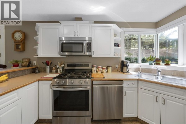 Kitchen with white cabinets, stainless steel appliances, gas range, and sink. - 205 Merlin Court, Kelowna