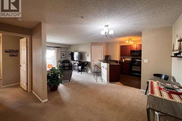 Living room and kitchen of an apartment with beige carpet. - 205 Third Avenue Unit# 1314, Invermere
