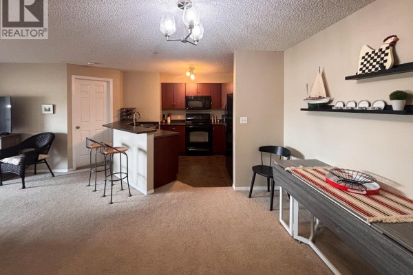 Apartment kitchen with dark wood cabinets and black appliances. - 205 Third Avenue Unit# 1314, Invermere