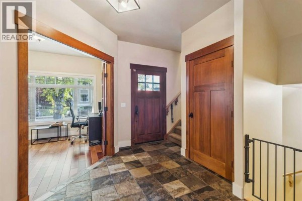 Interior foyer with dark wood trim, checkered tile floor, and a door to an office. - 2050 47 Avenue Sw, Calgary