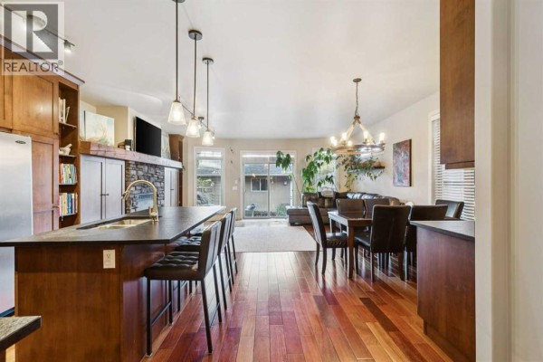 Open concept kitchen, dining area, and living room with wood floors and island. - 2050 47 Avenue Sw, Calgary