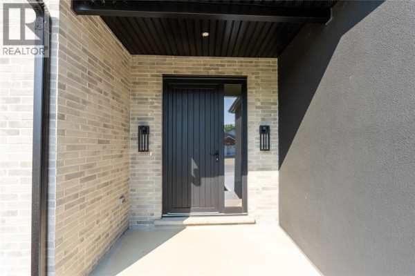 Close-up of the house entrance with concrete steps and black door. - 2056 Marion Avenue, Sarnia