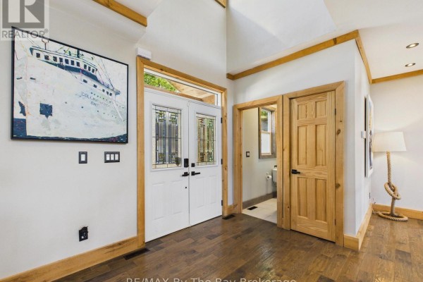 Interior foyer with double white doors, wooden trim, and artwork on wall. - 2056 River Road W, Wasaga Beach