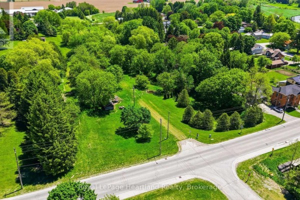 Aerial view of a large, treed lot with cleared grassy areas and a paved road. - 2057 William Street, Howick