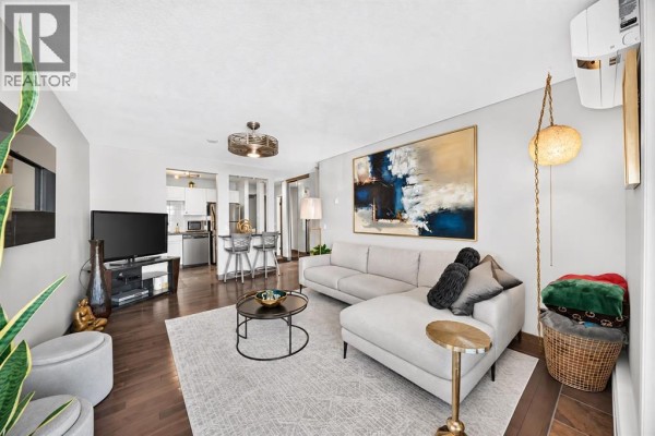 Living room with sectional sofa, TV, kitchen island with stools, and modern decor. - 206, 1810 11 Avenue Sw, Calgary