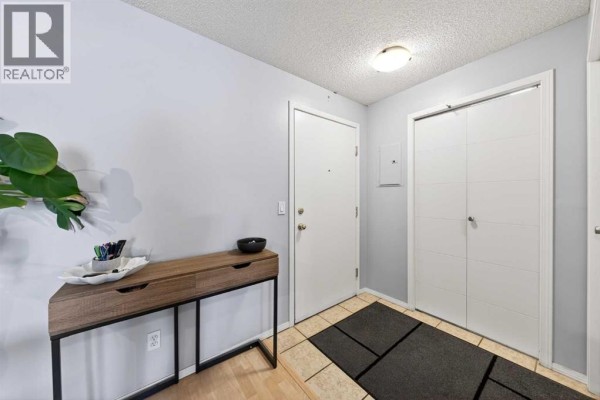 Apartment entryway with a console table, tile floor, and a bi-fold closet. - 206, 2000 Citadel Meadow Point Nw, Calgary