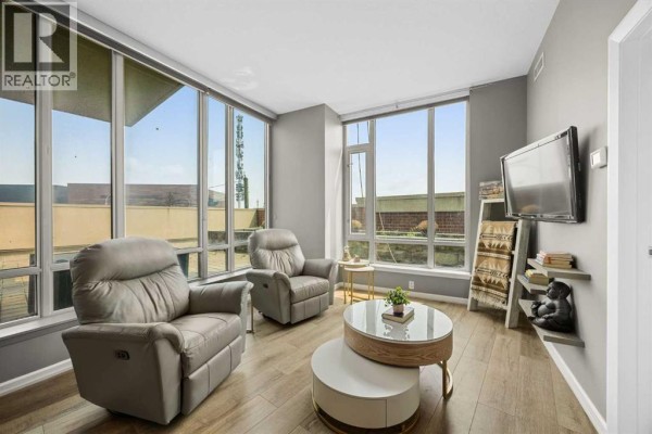U-shaped kitchen with dark wood cabinets, stainless steel appliances, and breakfast bar. - 206, 210 15 Avenue Se, Calgary