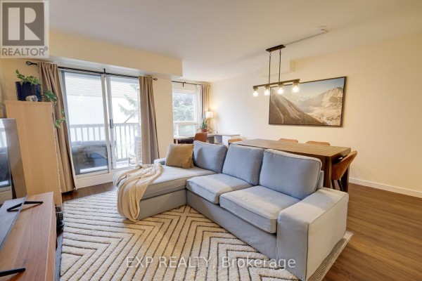 Living and dining area with a sectional sofa, dining table, and balcony view. - 206 - 12455 Ninth Line, Whitchurch Stouffville