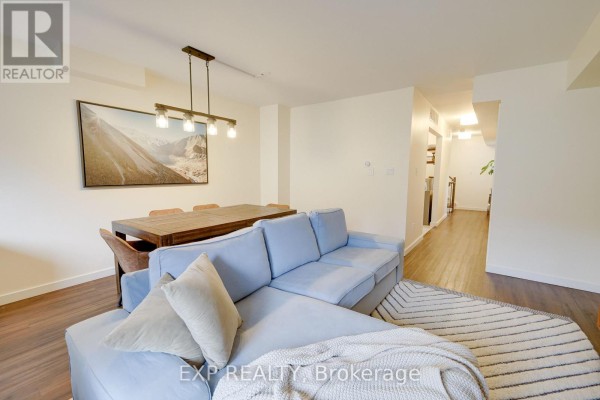 Open-concept living space with a sectional sofa, dining table, and hallway view. - 206 - 12455 Ninth Line, Whitchurch Stouffville