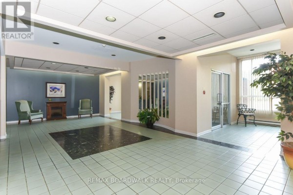 Apartment building lobby with tiled floors, seating, and decorative mirrors. - 206 - 330 Centrum Boulevard, Ottawa