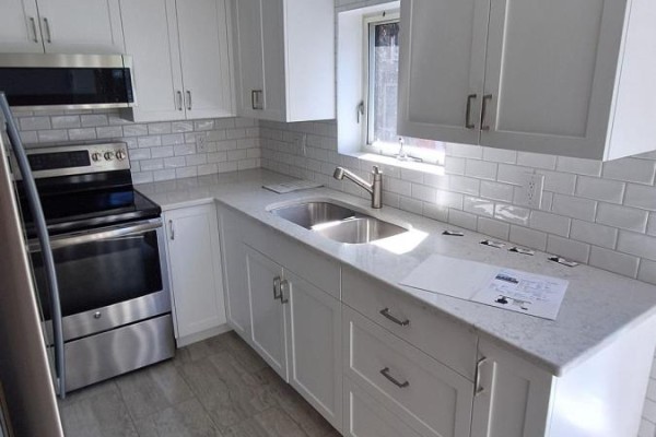 White kitchen with stainless steel appliances, subway tile backsplash, and granite countertops. - 206 - 330 Centrum Boulevard, Ottawa