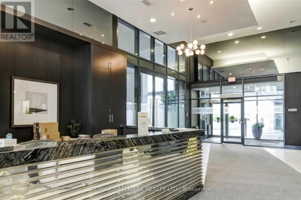 Lobby with marble reception desk, dark wood walls, glass doors, and contemporary chandelier. - 206 - 400 Adelaide Street E, Toronto