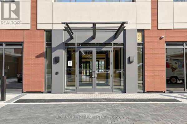 Modern building entrance with double glass doors and a metal awning. - 206 - 4010 Eglinton Avenue W, Toronto