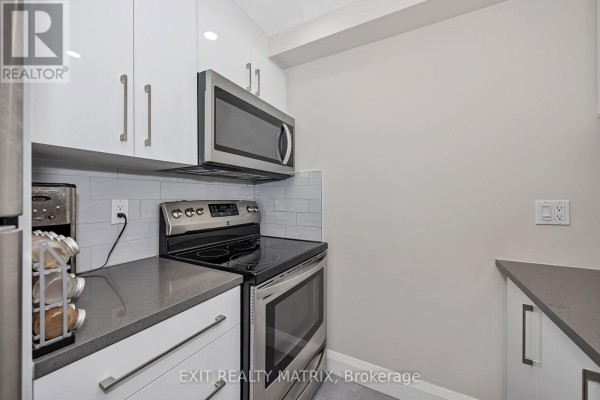 Close-up view of stainless steel stove and microwave in a modern kitchen. - 206 - 6532 Bilberry Drive, Ottawa
