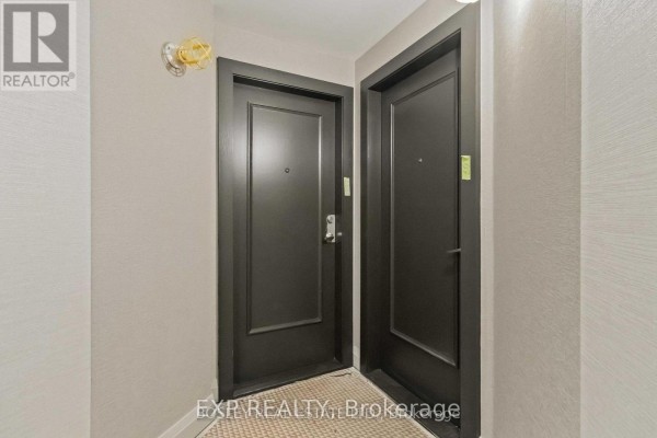 Hallway with two dark grey doors and textured beige walls leading to apartment entrances. - 206 - 7250 Yonge Street, Vaughan