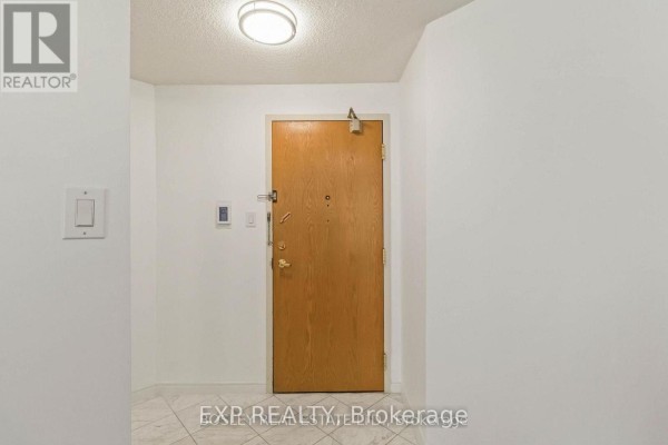 Interior view of a hallway with a light wood apartment door and white walls. - 206 - 7250 Yonge Street, Vaughan