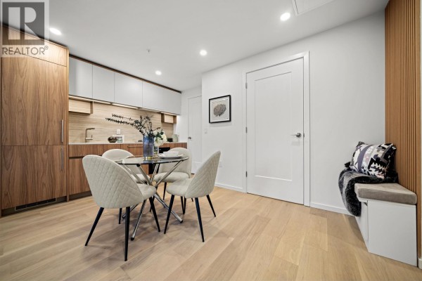 Bedroom with queen bed, nightstand, and large window with view of houses and trees. - 206 8486 Oak Street, Vancouver