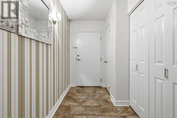 Apartment hallway with beige striped wallpaper, tiled floor, and white doors. - 206 85 Spinnaker Drive, Halifax
