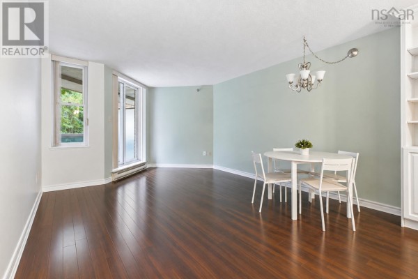 Living and dining area with dark sofa, coffee table, round dining table, and light blue walls. - 206 85 Spinnaker Drive, Halifax