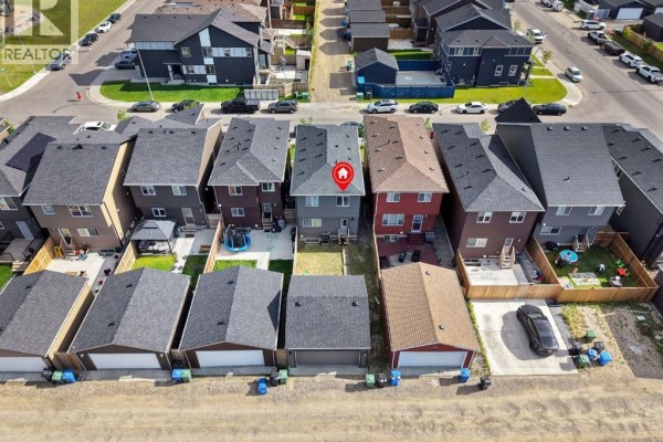 Aerial view of the backyards of several attached houses, some with garages and fences. - 206 Cornerstone Road Ne, Calgary