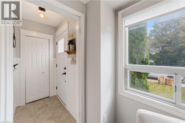 Interior view of a small entryway with a white door, closet doors, and a tiled floor. - 206 East 19th Street, Hamilton