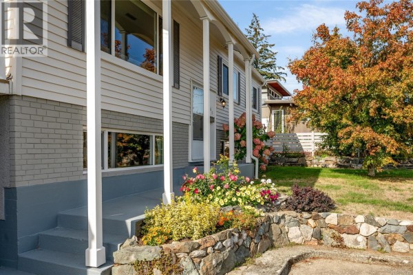 Close-up of the house entrance with steps, colorful flowers, and stone landscaping. - 2061 Forest Dr, Nanaimo
