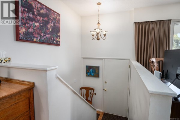 Interior view of a foyer with stairs, a door, and decorative artwork on the walls. - 2061 Forest Dr, Nanaimo