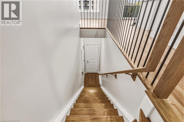 Wooden staircase with light grey walls and a railing leading to a lower level. - 2061 Prospect Street Unit# 211, Burlington