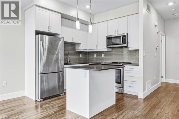 Modern kitchen with white cabinetry, stainless steel appliances, and a central island. - 2061 Prospect Street Unit# 211, Burlington
