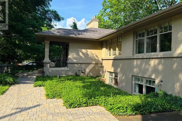 Side view of the house with green shrubbery and a stone walkway. - 2062 Glenforest Crescent, Oakville
