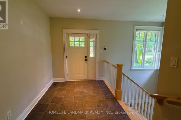 Interior view of the foyer with dark tiled floor and a wooden staircase. - 2062 Glenforest Crescent, Oakville